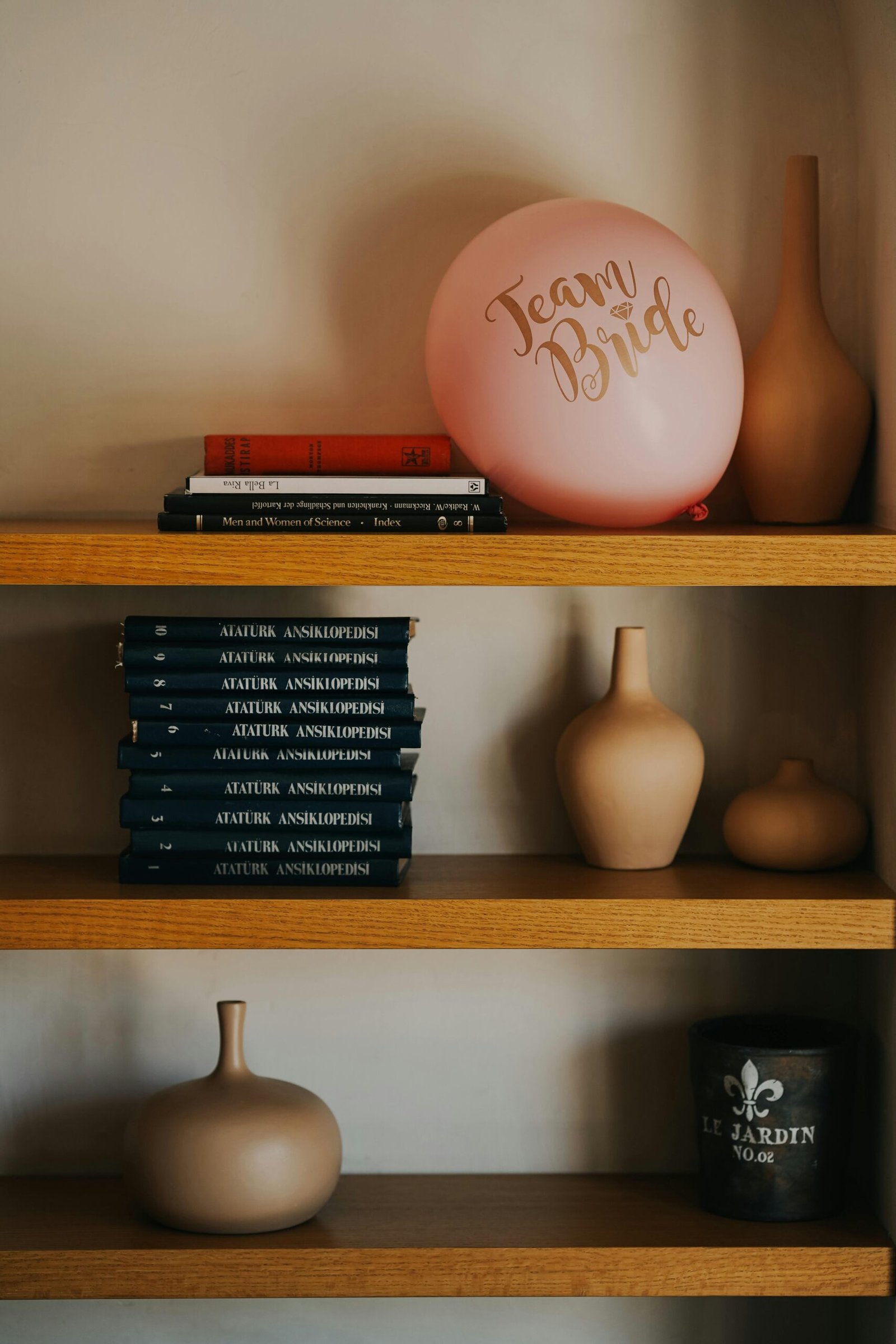 Stylish bookshelf with books, vases, and a 'Team Bride' balloon in Ankara, Türkiye, creating a chic still life scene.